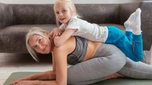A senior woman and her young grandchild bonding during a fun yoga session indoors.
